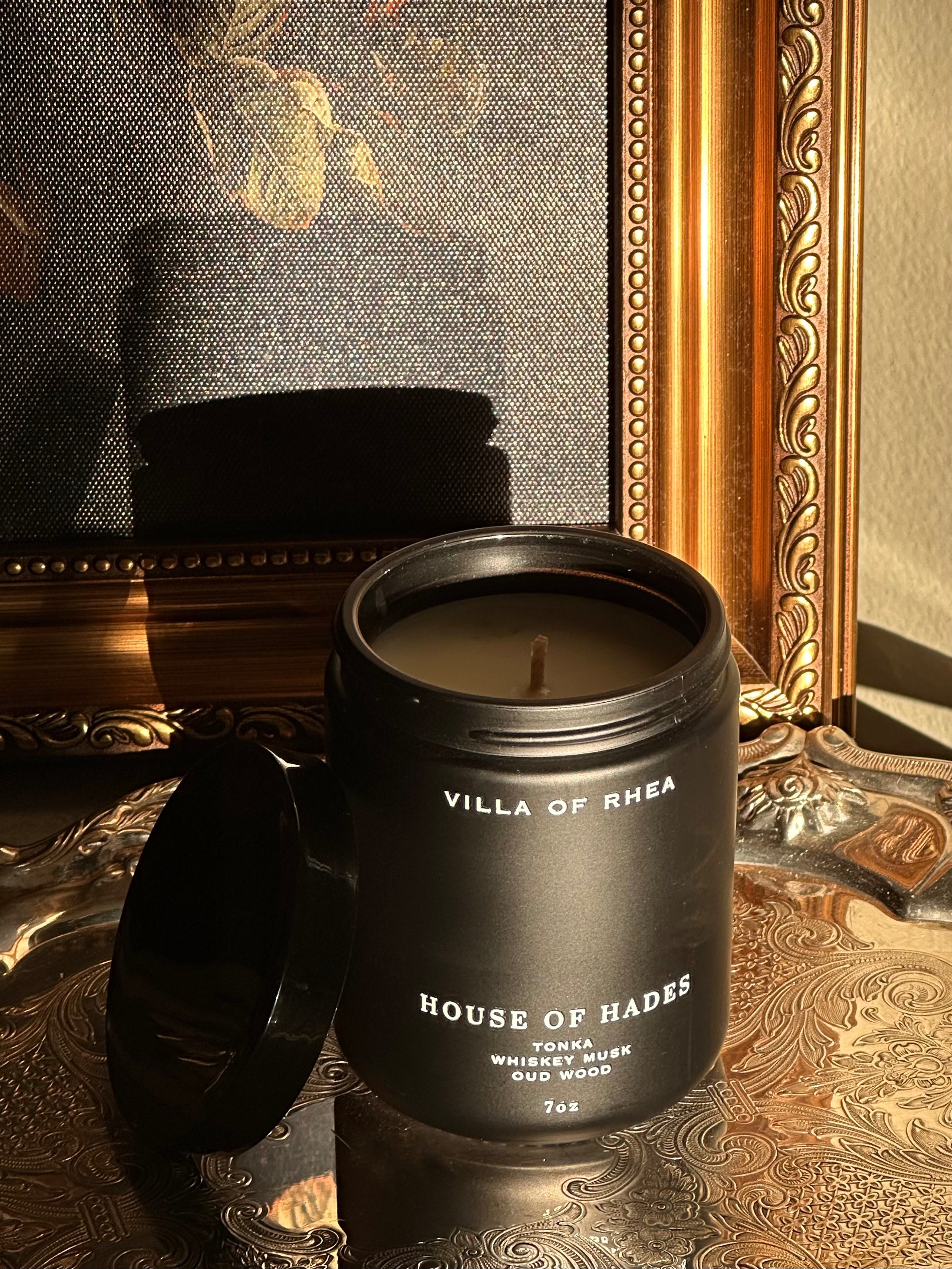 House of Hades candle on a decorative surface with a mirror in the background. tonka, whiskey musk and oud wood scent.Vintage style. greek mythology inspired. luxurious soy wax candies.
