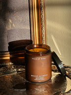 Mount Olympus candle on a decorative surface with a mirror in the background. leafy greens, salty marine, woodland forest scent . Vintage style. greek mythology inspired. luxurious soy wax candies.