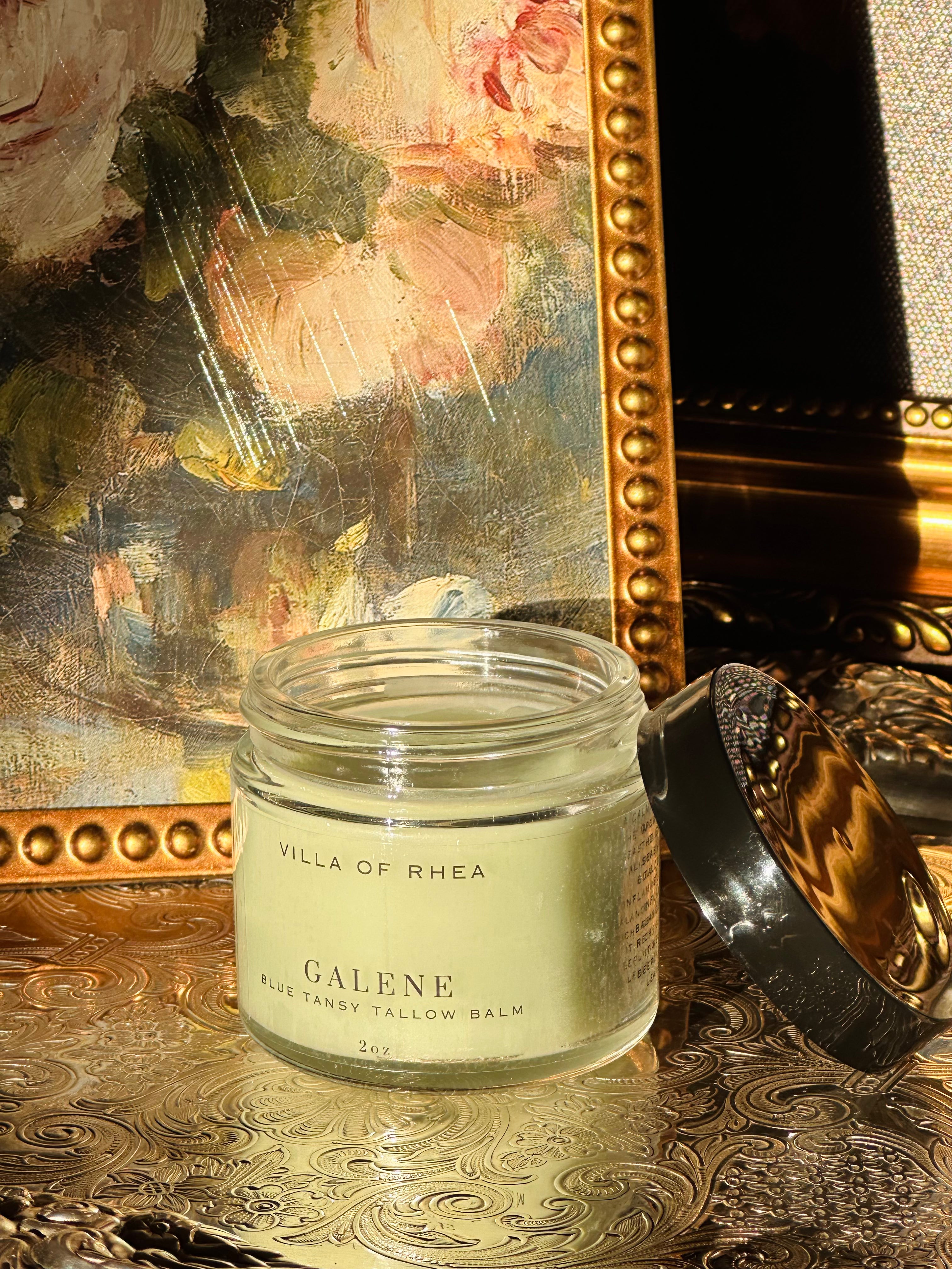 Jar of 'Galene Blue Tansy Tallow Balm' from 'Villa of Rhea' on a decorative surface with a mirror and statue in the background. Vintage style. Greek Mythology Inspired. Luxury tallow balm. luxurious handmade tallow balm.