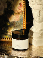 Jar of 'Gaia Tallow Balm' from 'Villa of Rhea' on a decorative surface with a mirror and statue in the background. Vintage style. Greek Mythology Inspired. Luxury tallow balm. luxurious handmade tallow balm.