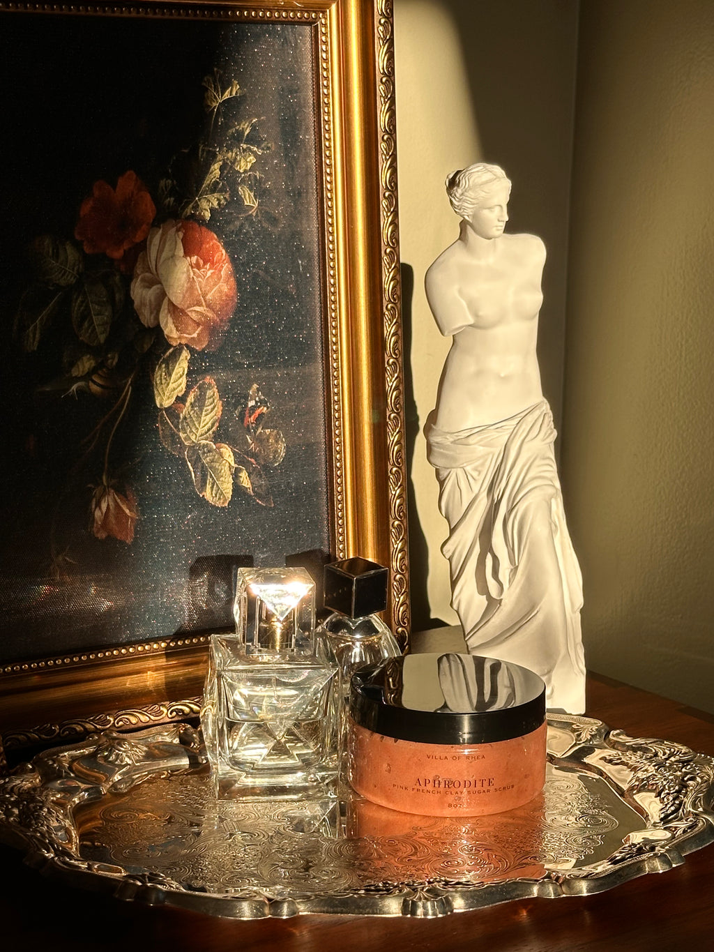 Sugar scrub named 'Aphrodite' on a reflective surface with classical sculpture in the background .Vintage style. Greek Mythology Inspired. Luxury body scrub. handmade body scrubs.