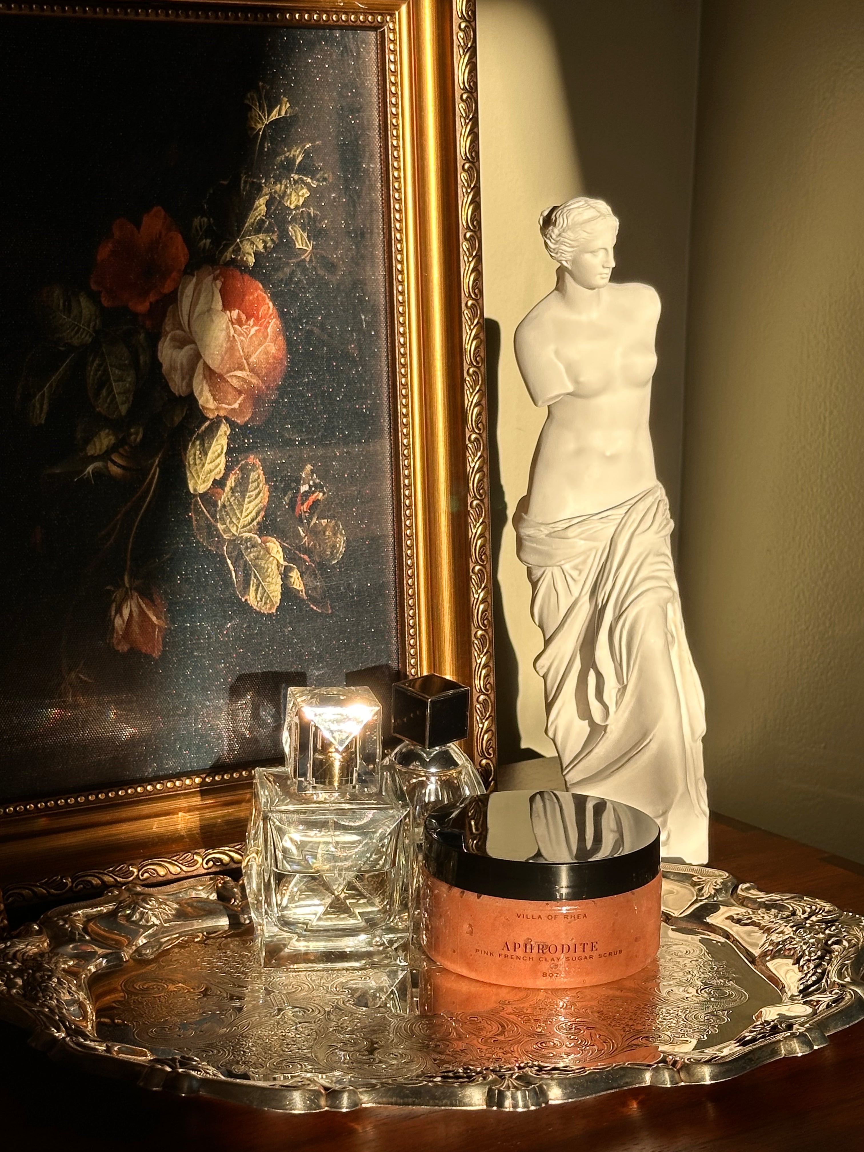 Sugar scrub named 'Aphrodite' on a reflective surface with classical sculpture in the background .Vintage style. Greek Mythology Inspired. Luxury body scrub. handmade body scrubs.