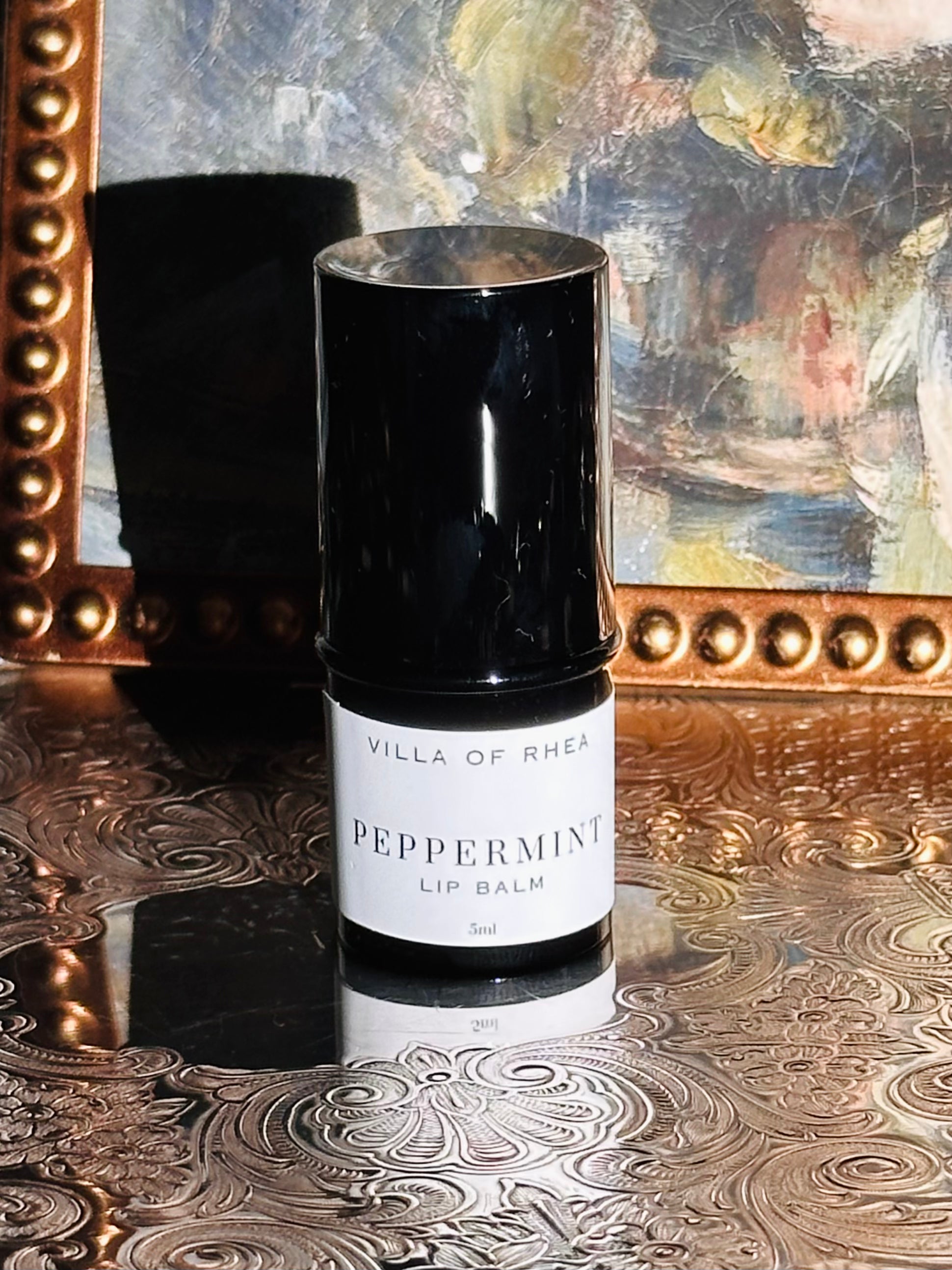 Villa of Rhea Grapefruit Lip Balm on a decorative surface with a textured background.Vintage style. Greek Mythology Inspired. Luxury lip balm. luxurious handmade lip balm