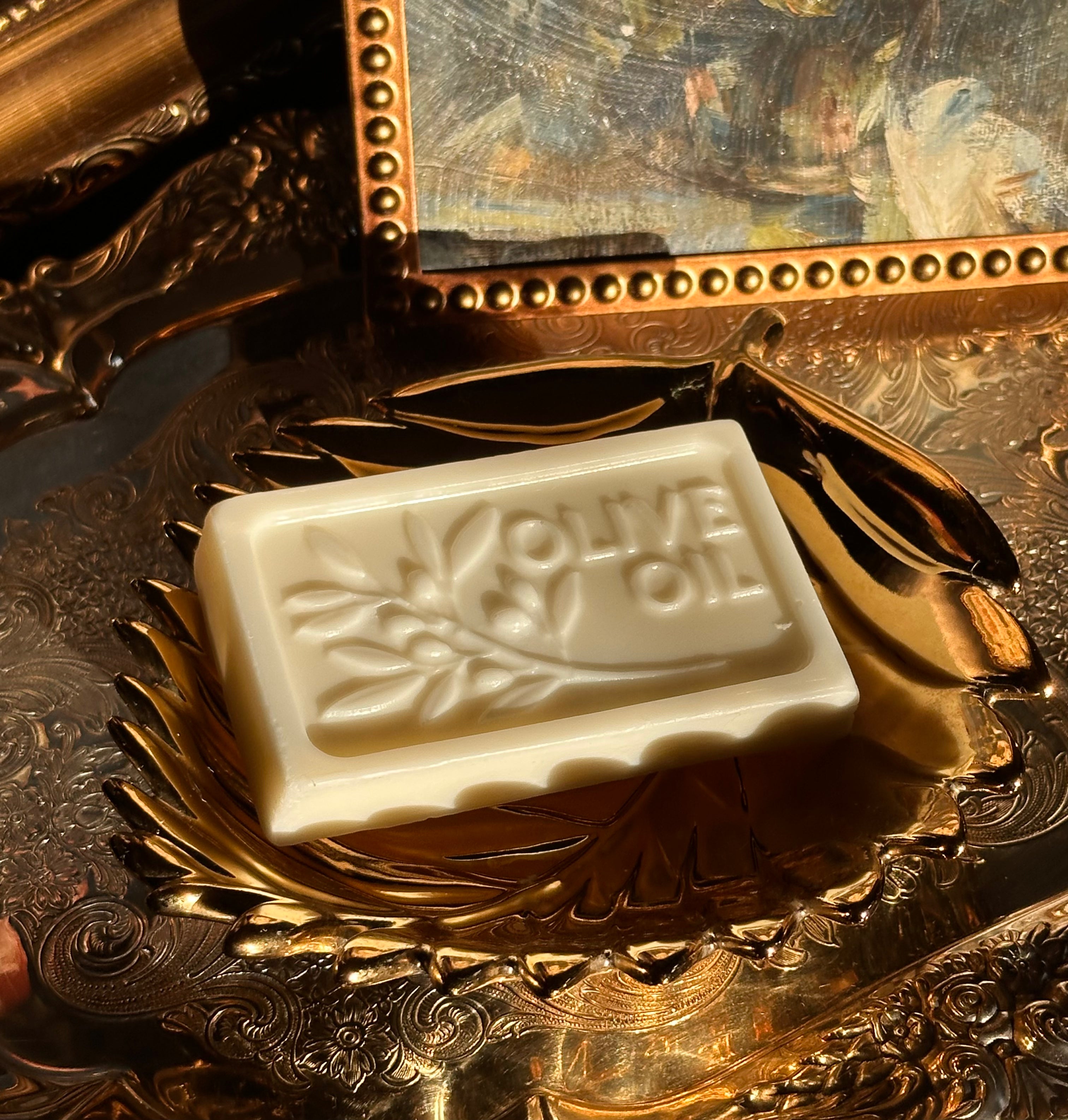 Bar of olive oil soap on a decorative gold tray with a reflective background.Vintage style. Greek Mythology Inspired. Luxury Goats milk soap