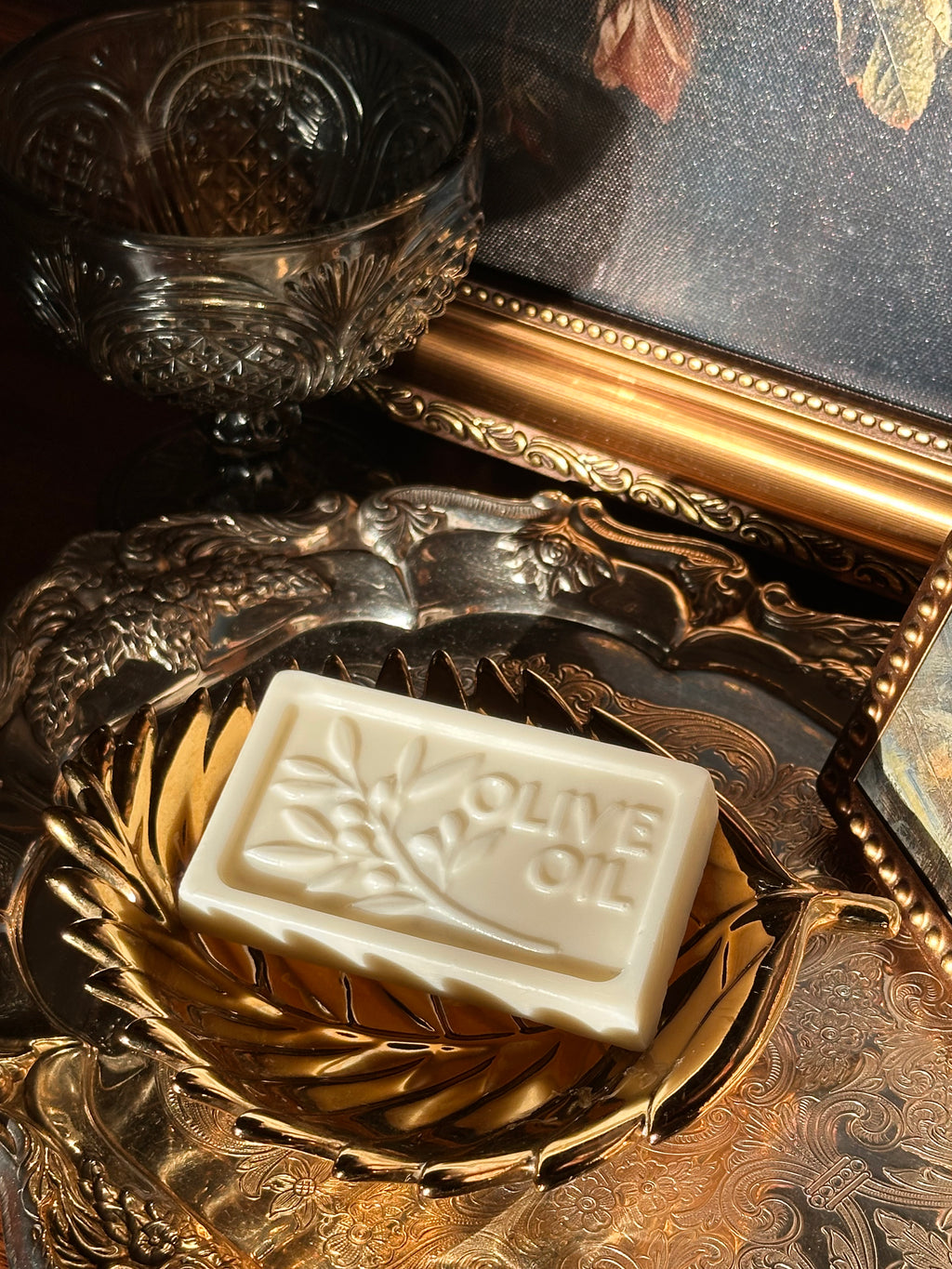 Bar of olive oil soap on a decorative gold soap dish with a reflective surface in the background. Vintage style. Greek Mythology Inspired. Luxury Goats milk soap
