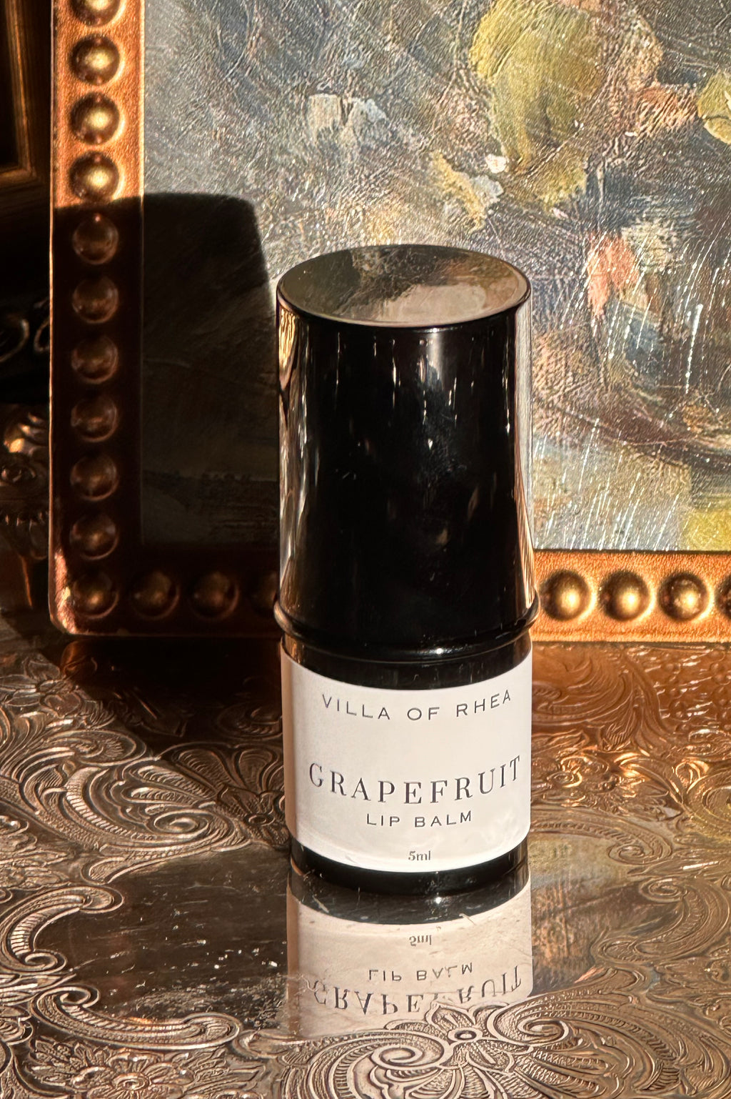 Villa of Rhea Grapefruit Lip Balm on a decorative surface with a textured background.Vintage style. Greek Mythology Inspired. Luxury lip balm. luxurious handmade lip balm