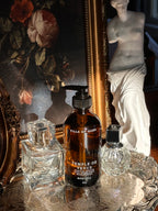 Villa of Rhea body oil bottle with classical statue and floral painting in the background.Temple of Venus Body Oil. Vanilla Scent. Orchid Scent. Hydrangea and Sandalwood Fragrance. Aphrodite Goddess. Greek Mythology inspired. Vintage Modern Style. All Natural body oil. Non-toxic Body Care. Healthy Clean Beauty. Green Beauty. Healthy Body Oil